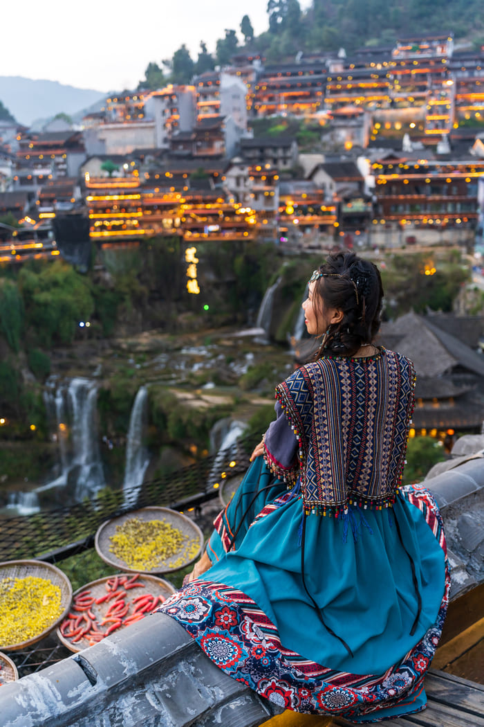 Una mujer sentada contemplando la ciudad de ciudad-lijiang
